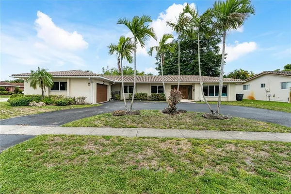 a front view of a house with a garden and palm trees