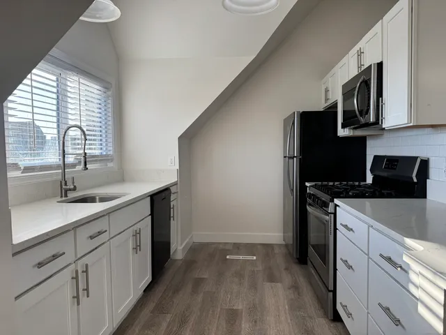 a kitchen with stainless steel appliances granite countertop a sink a stove a microwave and wooden floors