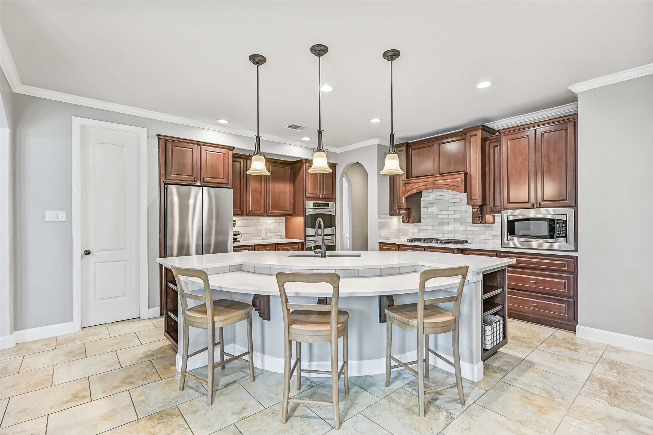 1008 Point Isabel Lane Friendswood, TX 77546 - Photo 13 of 50 Continue beyond the dining room into an updated island kitchen with gleaming quartz countertops, pendant lighting, and a sweeping breakfast bar with seating. Also note the stained cabinetry, stainless appliances, and MUST-SEE pantry with pull outs.