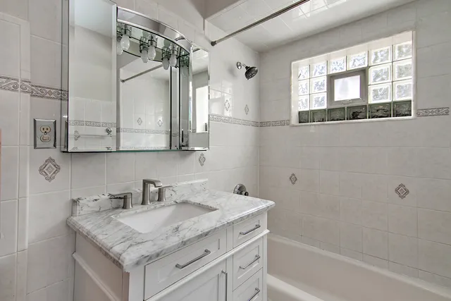 a bathroom with a granite countertop sink a mirror a vanity and a bathtub