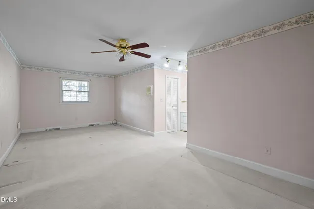 an empty room with a window and a fan