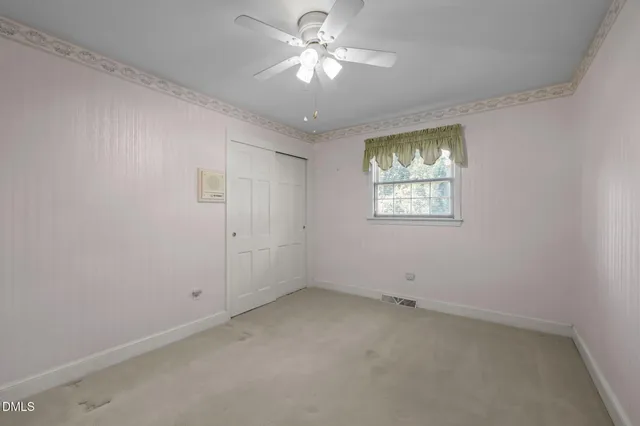 an empty room with windows and fan
