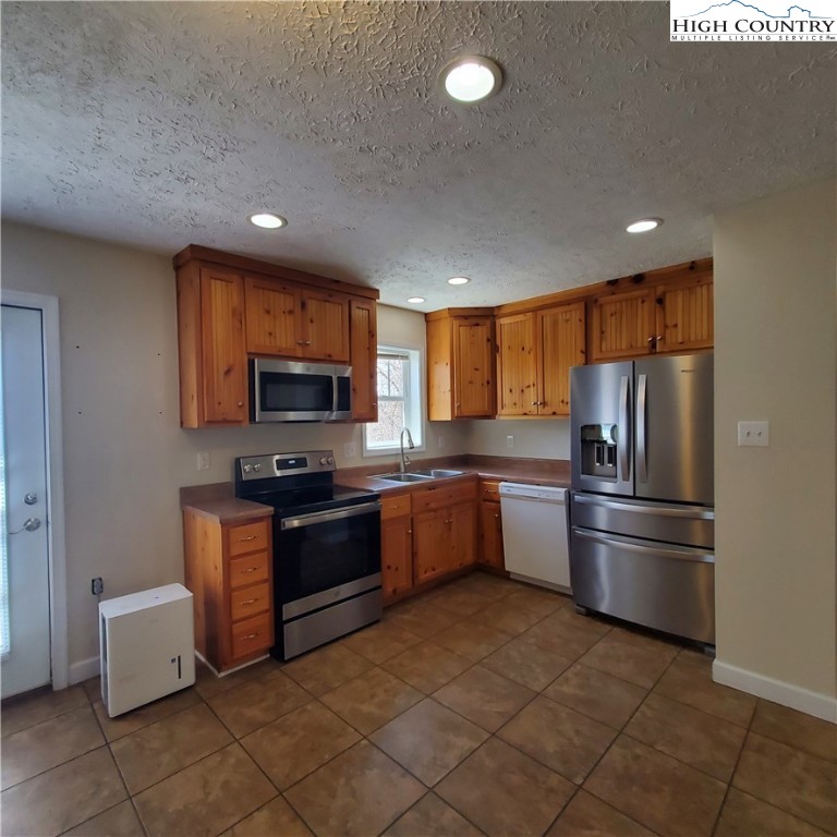 161 Alexander Drive Boone, NC 28607 - Photo 7 of 28 a kitchen with granite countertop a refrigerator and a stove top oven
