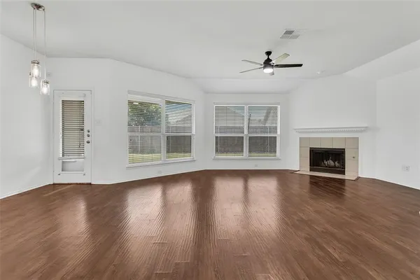 an empty room with wooden floor fireplace and windows