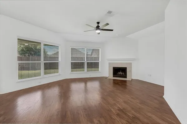 a view of an empty room with wooden floor fireplace and a window