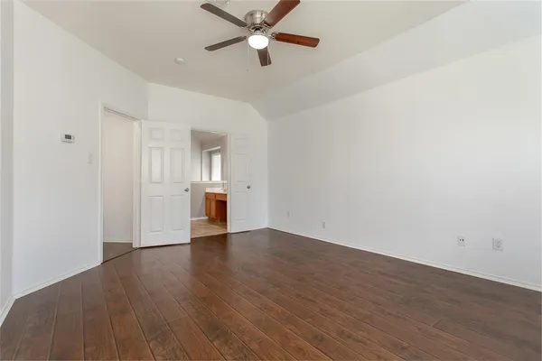 an empty room with wooden floor a ceiling fan and windows