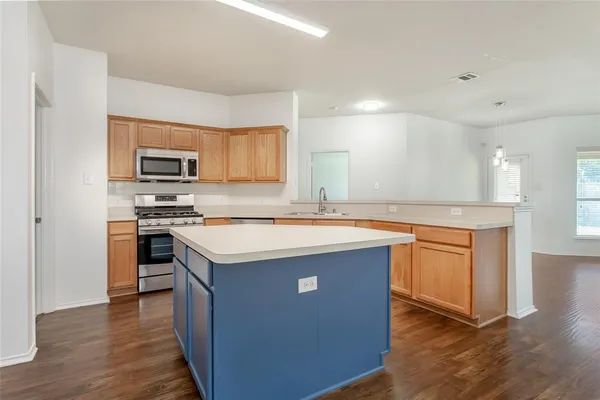 a kitchen with stainless steel appliances granite countertop a stove a sink and a microwave