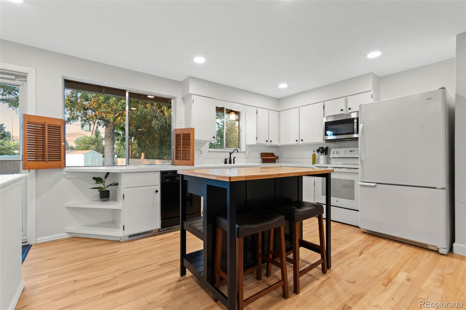 5366 Field Circle Arvada, CO 80002 - Photo 13 of 50 a kitchen with a sink a microwave a refrigerator and white cabinets with wooden floor