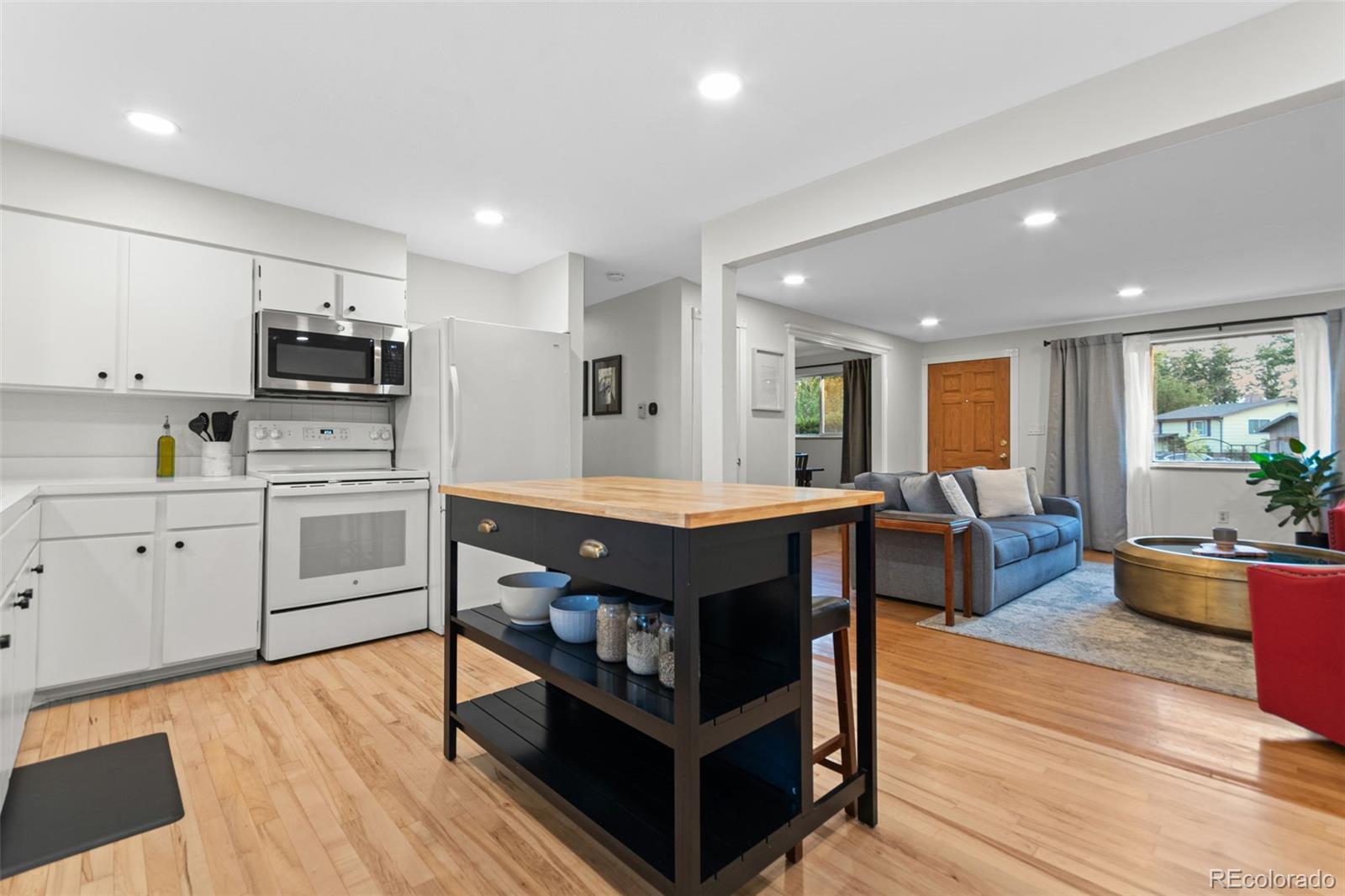 5366 Field Circle Arvada, CO 80002 - Photo 14 of 50 a kitchen with stainless steel appliances a stove a sink dishwasher a microwave oven and a dining table with wooden floor