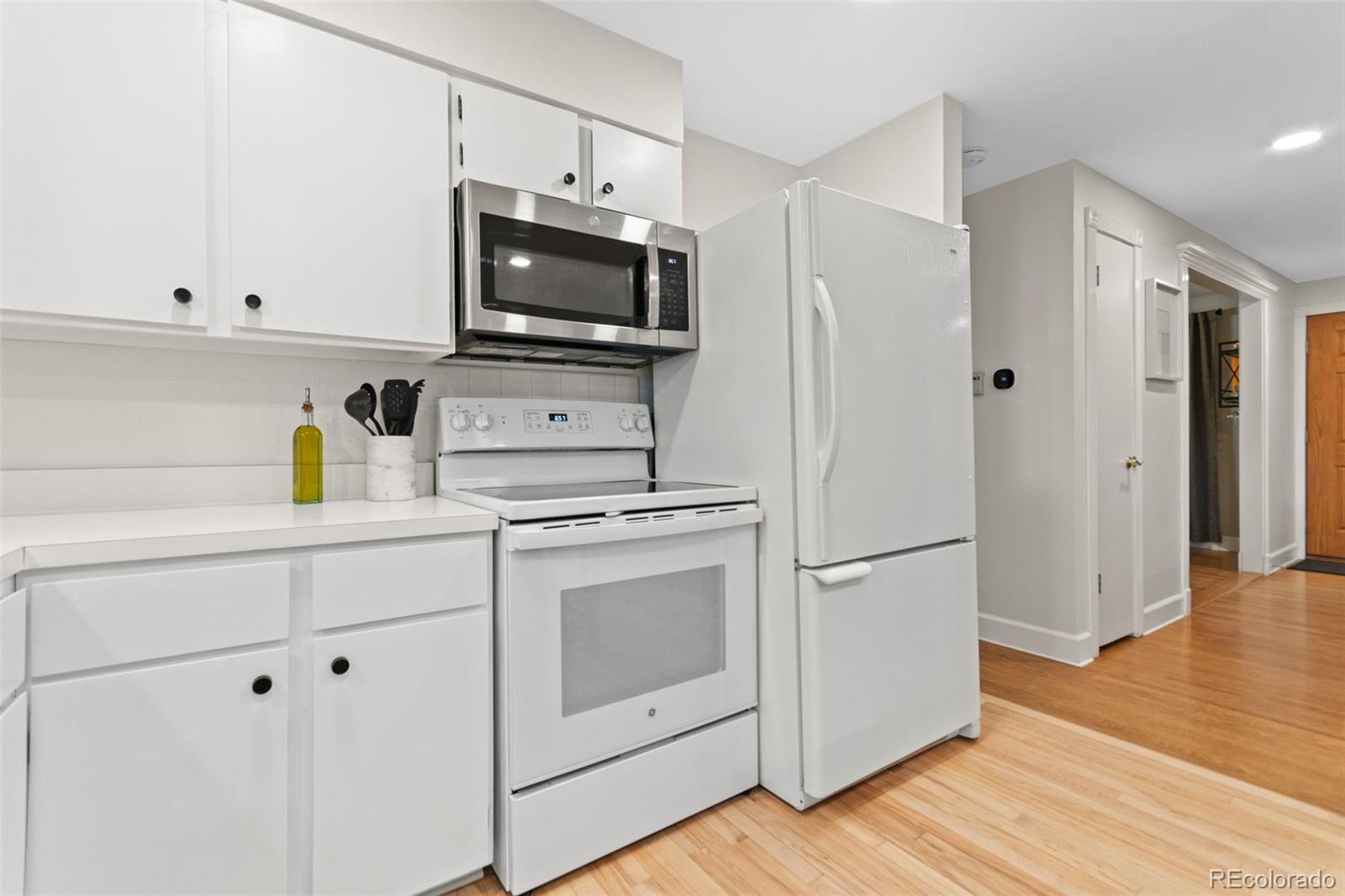 5366 Field Circle Arvada, CO 80002 - Photo 17 of 50 a kitchen with white cabinets stainless steel appliances and wooden floor