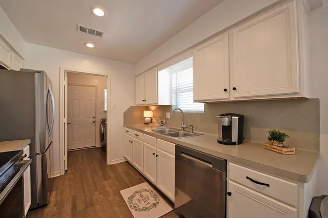 a kitchen with granite countertop a sink stainless steel appliances and cabinets