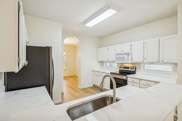 a kitchen with stainless steel appliances a stove a refrigerator a sink a stove top oven a dining table and chairs