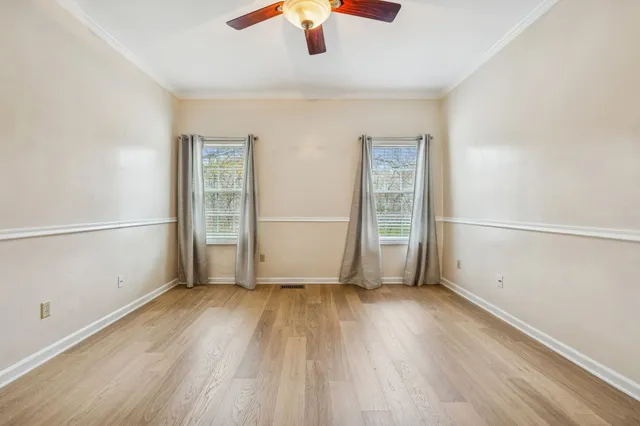 an empty room with wooden floor cabinet and windows
