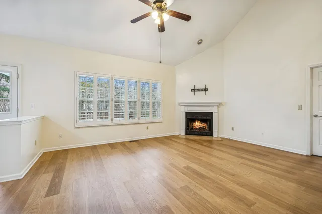 a view of an empty room with wooden floor fireplace and a window