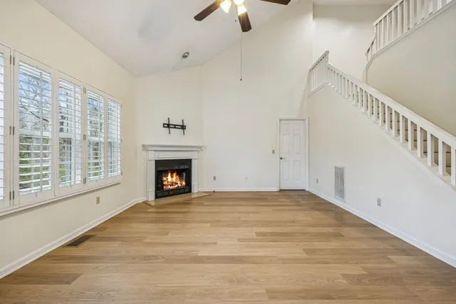 a view of an empty room with chandelier fan and fire place