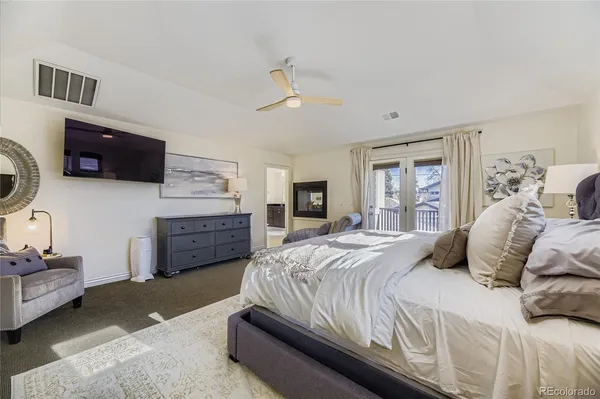 a bedroom with a bed couches and a flat tv screen