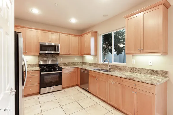 a kitchen with stainless steel appliances granite countertop a stove a sink and a microwave