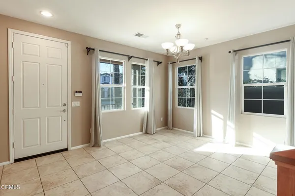 a view of an empty room with window and chandelier