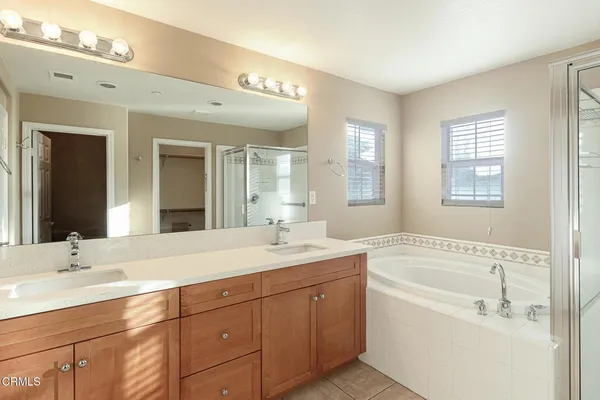 a bath room with a sink vanity tub and a mirror