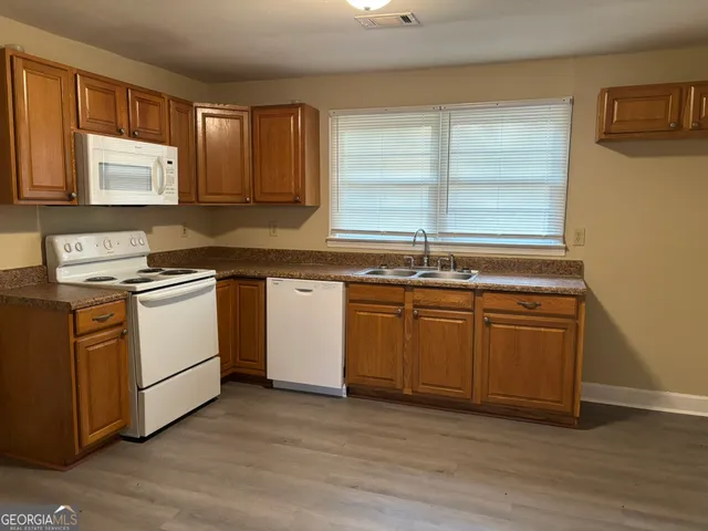 a kitchen with sink a microwave and cabinets