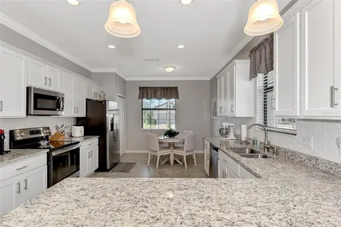 a kitchen with stainless steel appliances granite countertop a sink dishwasher a refrigerator oven a stove with island and chairs