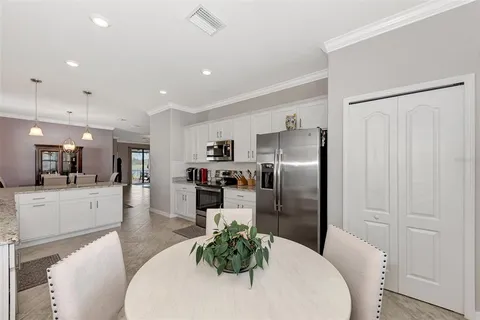 a kitchen with stainless steel appliances kitchen island granite countertop a refrigerator a stove a sink a dining table and chairs