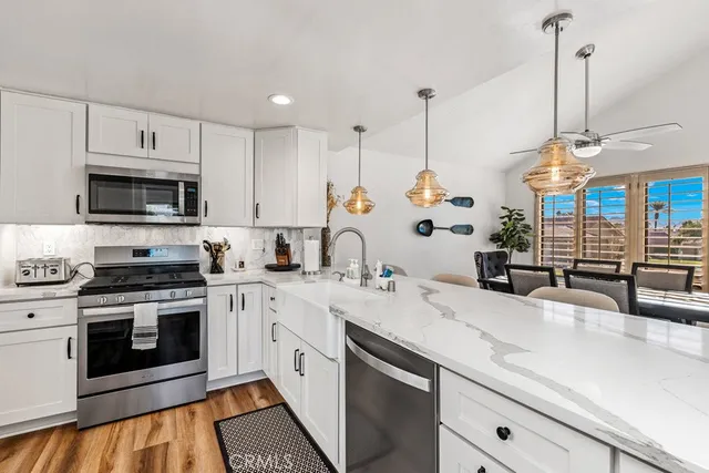 a kitchen with stainless steel appliances granite countertop a sink a stove and a wooden floors