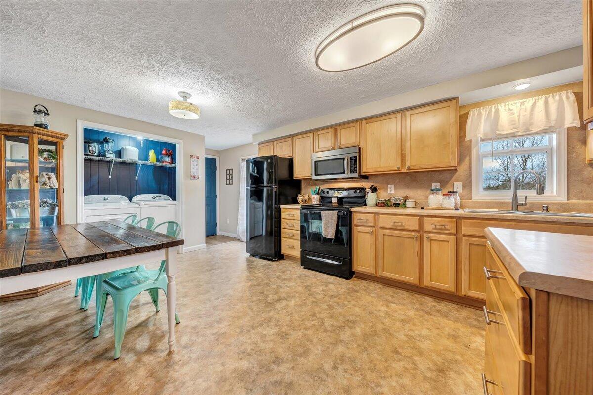 2152 Egg Farm Road Patrick Springs, VA 24133 - Photo 7 of 32 a kitchen with stainless steel appliances granite countertop a stove top oven a sink a dining table and chairs