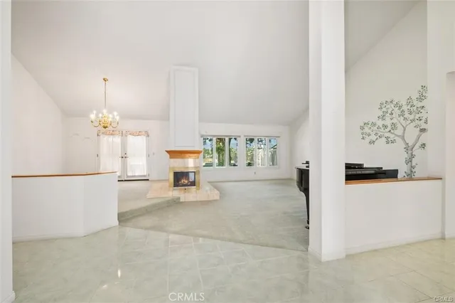 a view of an empty room with chandelier fan and fireplace