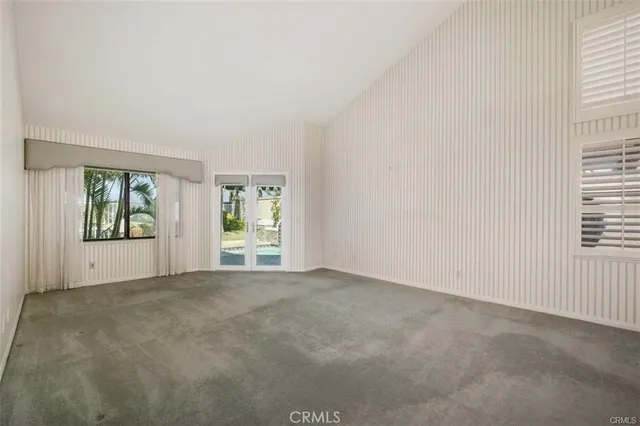 a view of an empty room with a window and a kitchen