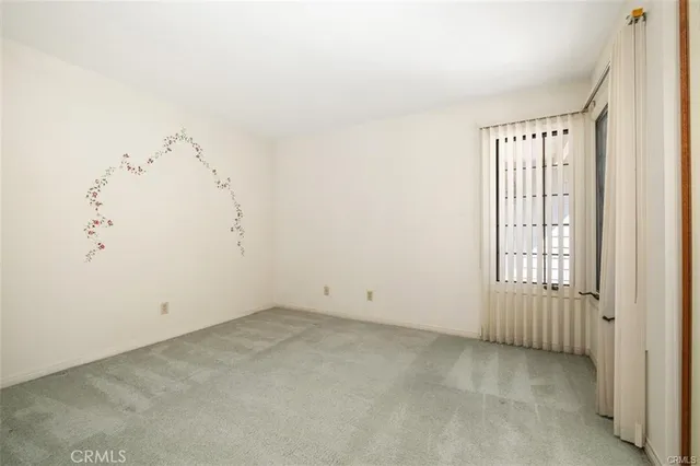 a view of an empty room with a window and cabinet
