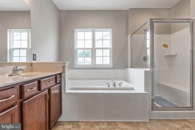 a bathroom with a tub sink shower and mirror