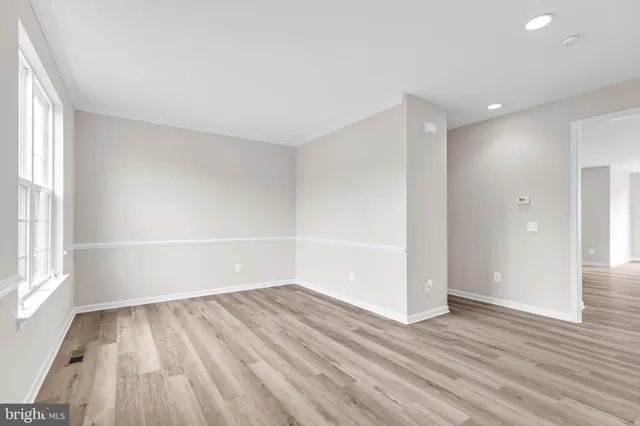 a view of an empty room with wooden floor ceiling fan