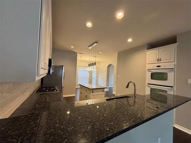 a kitchen with stainless steel appliances granite countertop a sink a stove and a refrigerator