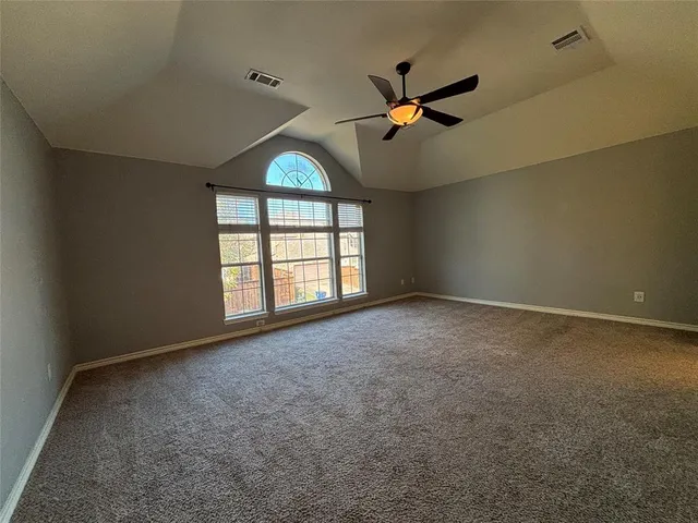 an empty room with windows and ceiling fan