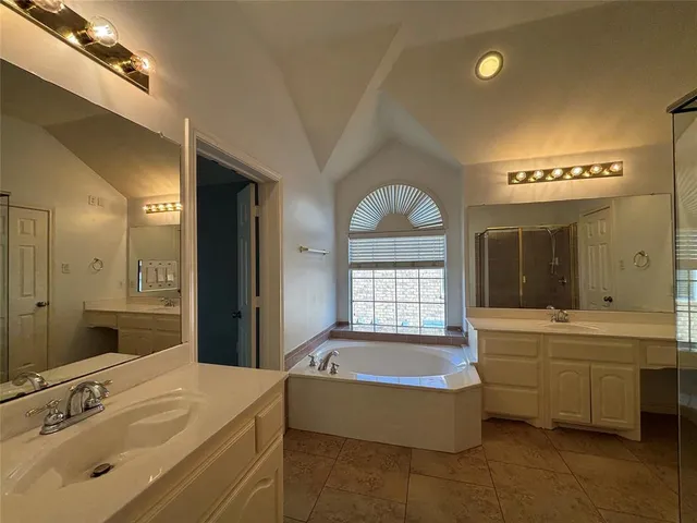 a spacious bathroom with a tub sink and mirror
