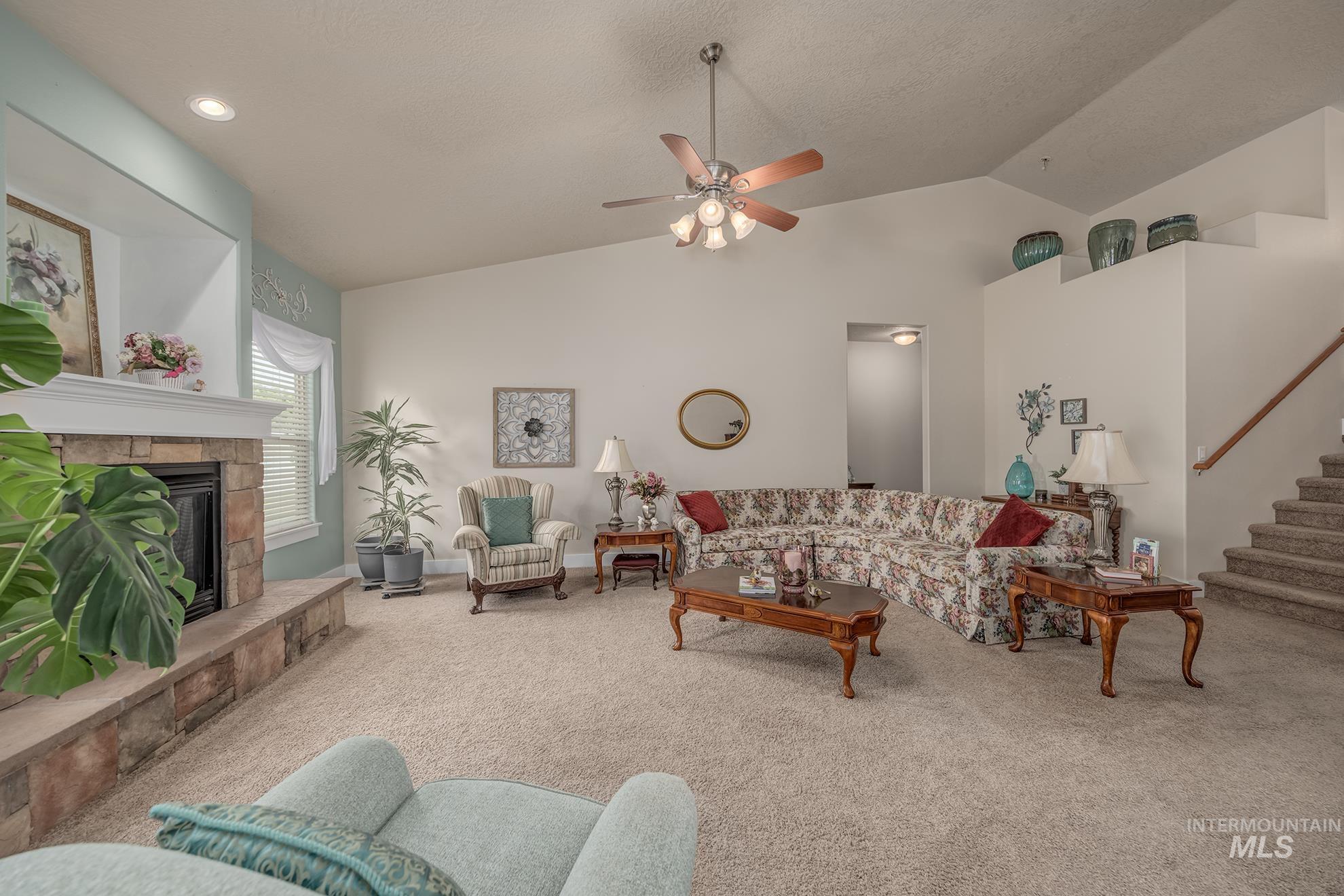 420 West Indianhead Road Weiser, ID 83672 - Photo 8 of 40 Spacious living area featuring a stone-faced fireplace with a mantel, vaulted ceilings, and a ceiling fan