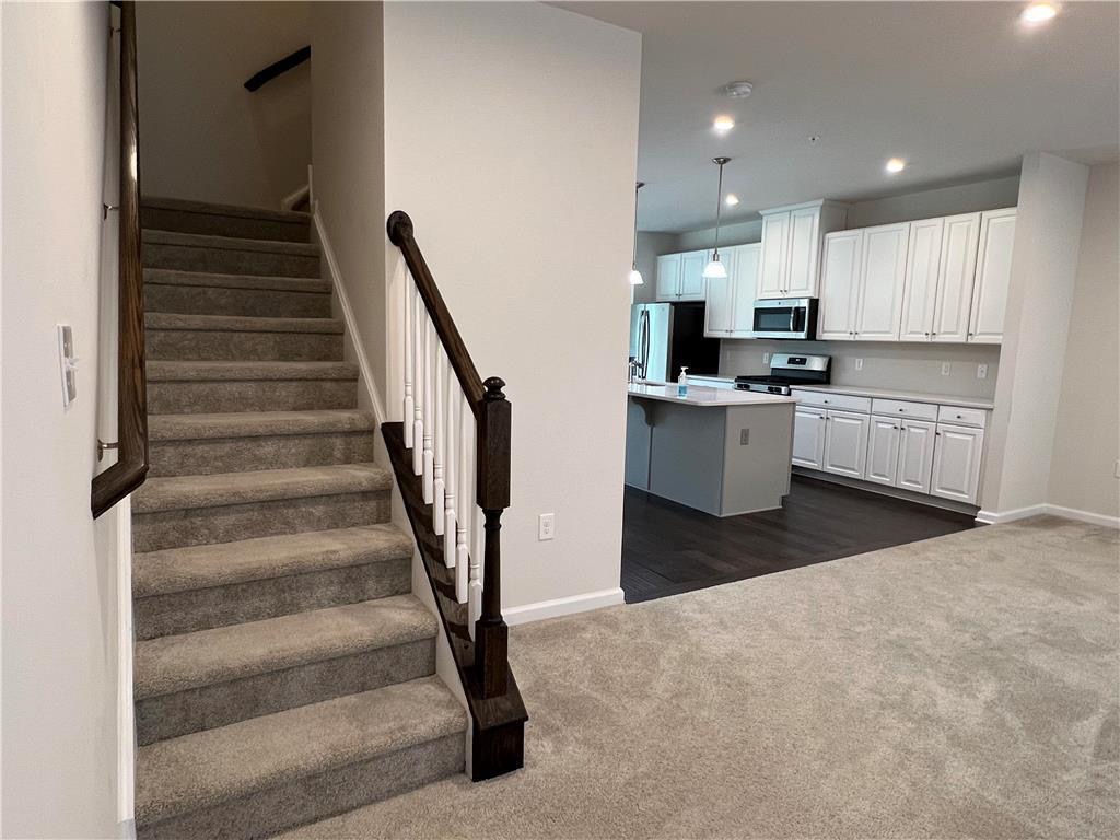 2356 Raya Way Easton, PA 18045 - Photo 10 of 28 Plush carpeted stairs lead upward adjacent to an open-concept kitchen and living area.
