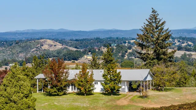 an aerial view of residential houses with outdoor space and trees