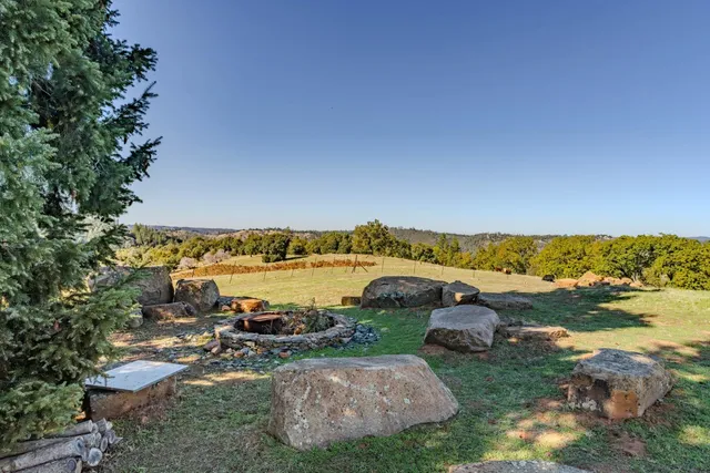 a view of a lake with lawn chairs and large trees