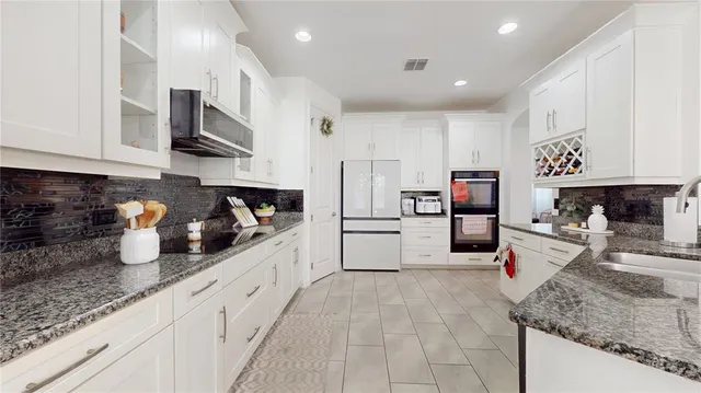 a kitchen with stainless steel appliances granite countertop a sink refrigerator and cabinets