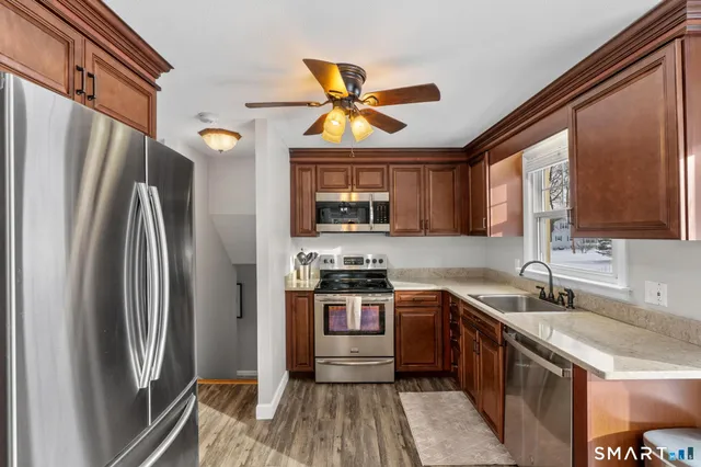 a kitchen with stainless steel appliances granite countertop a refrigerator a sink a stove and white cabinets