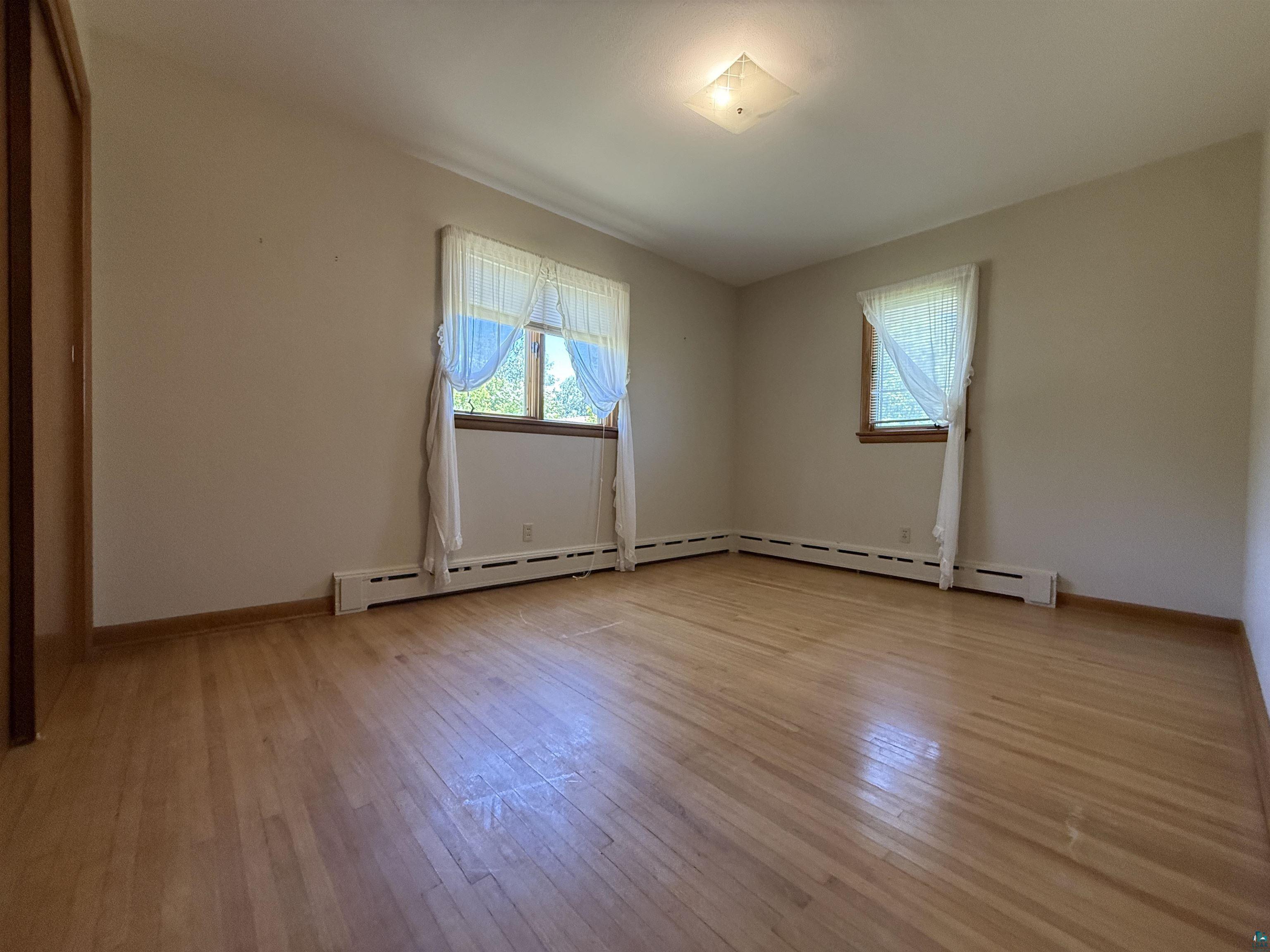 607 3rd Street Northeast Chisholm, MN 55719 - Photo 15 of 32 Room featuring wood-finish flooring, two windows with wood trim, and a ceiling-mounted light fixture