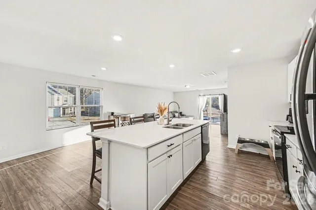 a kitchen with a sink stove and wooden floor