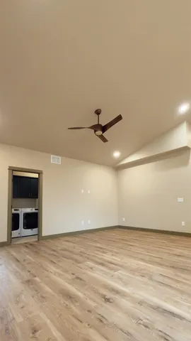 an empty room with wooden floor a ceiling fan and windows