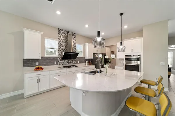 a kitchen with sink a refrigerator and chairs