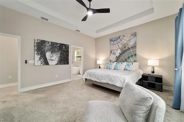 a bedroom with a bed lamp and paintings on the wall