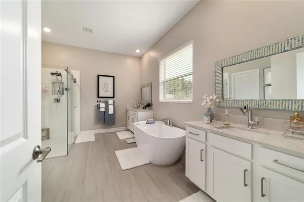 a spacious bathroom with a double vanity sink mirror and bathtub