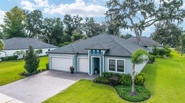 an aerial view of a house with swimming pool and large trees