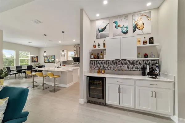 a living room with furniture a chandelier and kitchen view